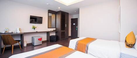 A hotel room with two beds, a desk, a chair, a TV, and a mirror.
