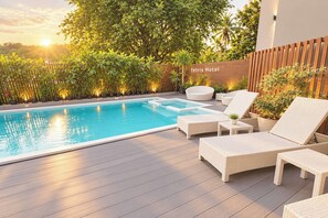 Una piscina con sillas de descanso y una terraza de madera.