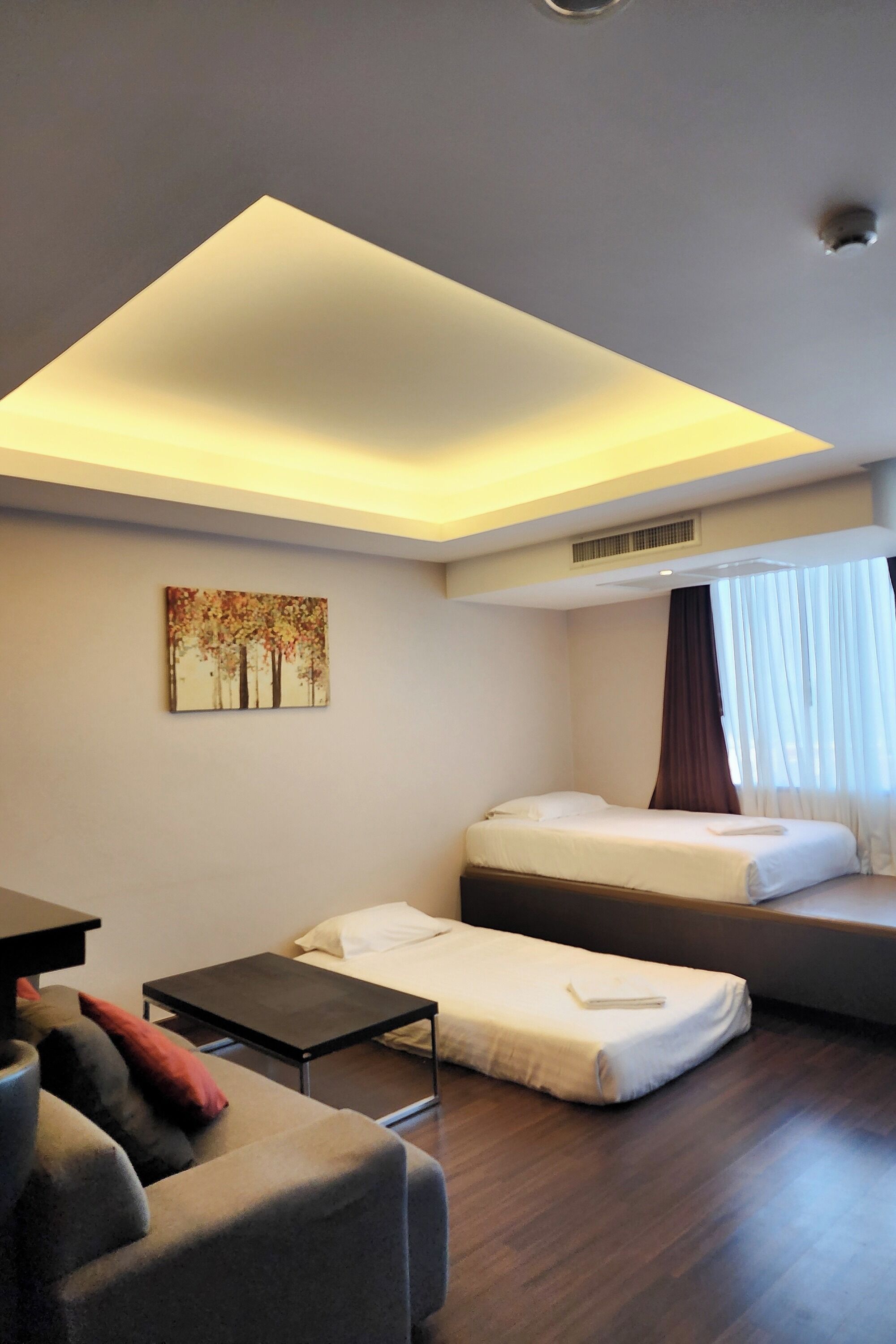 Una habitación de hotel moderna con cama, sofá, una mesita y una lámpara en el techo.