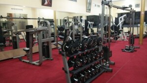 A gym with various exercise equipment, including dumbbells and weight machines, arranged on a red carpeted floor. - Hotel Ramayana Garut (Garut)