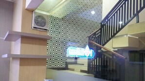 A modern interior with a patterned wall, a neon sign, and a staircase. - Hotel Ramayana Garut (Garut)