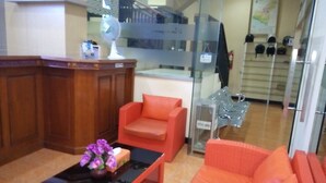 A lobby with a reception desk, a sofa, a coffee table with flowers, and a display of helmets. - Hotel Ramayana Garut (Garut)
