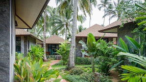 A resort with multiple bungalow-style buildings, a well-maintained garden with various tropical plants, and a paved pathway. - Medee Resort (Ko Kood)