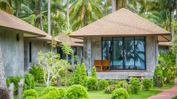 A resort with modern, minimalist architecture, featuring large windows and a well-maintained garden with various plants and a pathway.