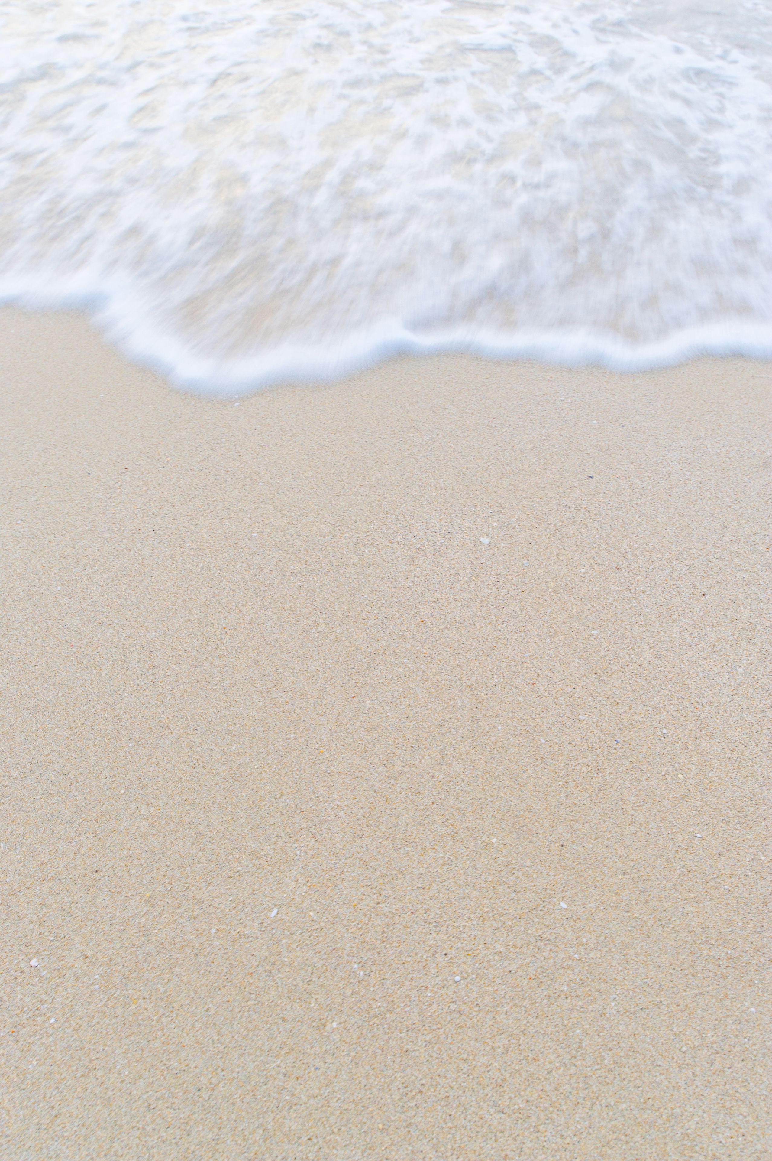 A sandy beach with gentle waves lapping at the shore.