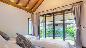 A bedroom with two beds, large windows, and a view of a garden.