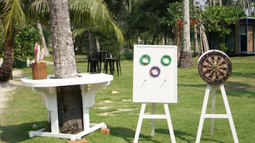 Relax in a serene outdoor setting with a table and chairs surrounded by palm trees and a nearby structure.