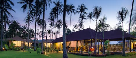 Un resort con varias construcciones, palmeras y un césped bien cuidado.