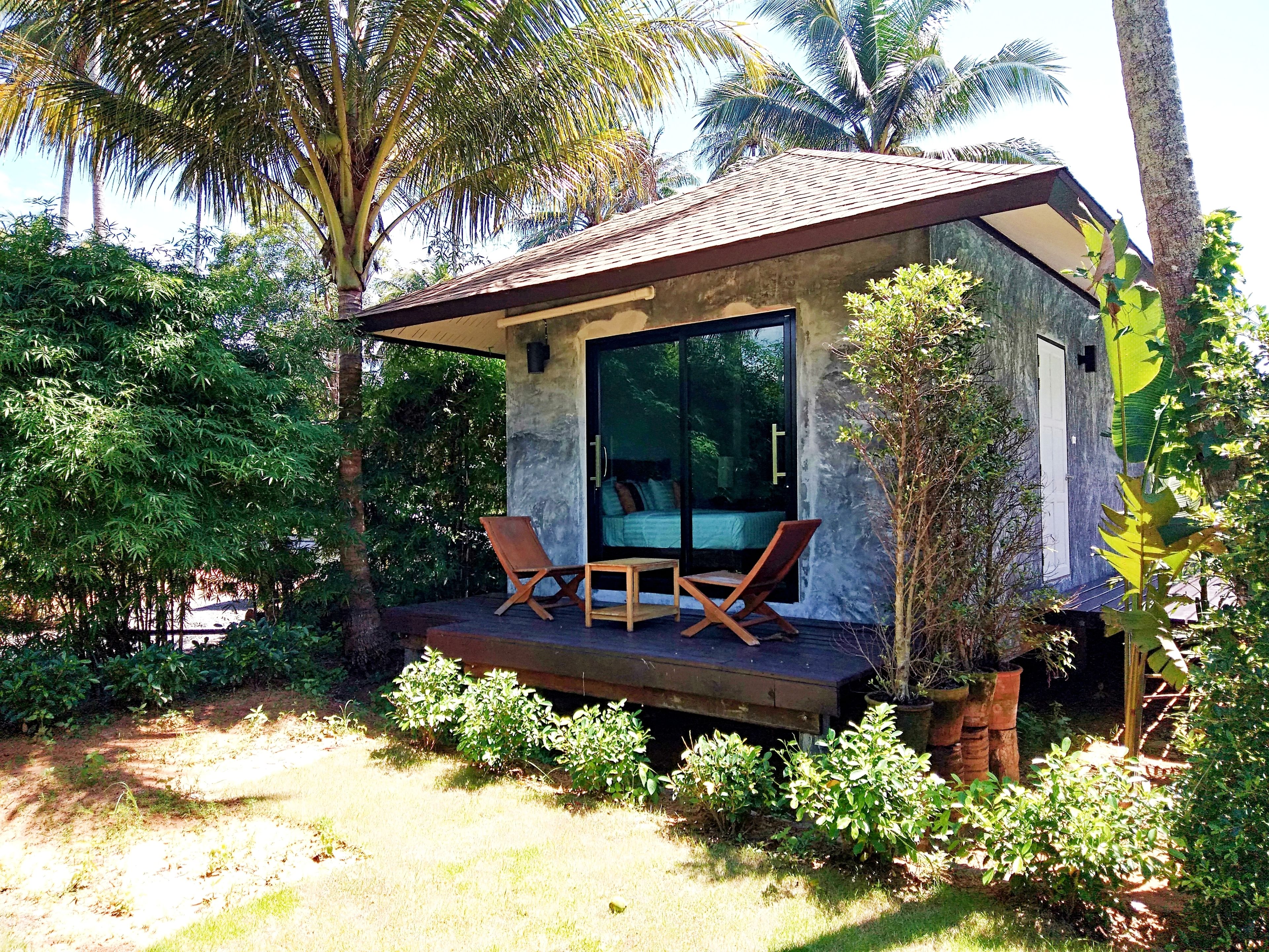 Een klein huis met balkon, tafel en twee stoelen.