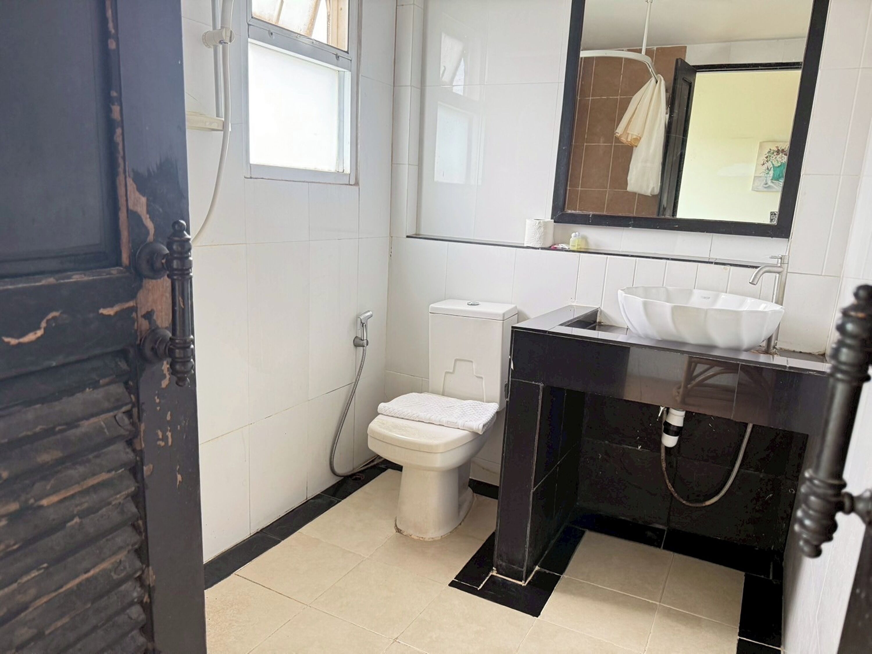 A bathroom with a toilet, sink, and window.