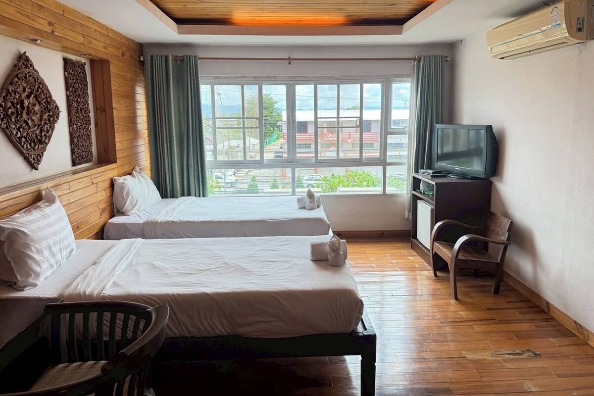 Habitación de hotel con dos camas, un televisor y vista a la ciudad.