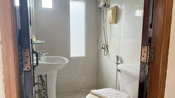 A small, clean bathroom with a toilet, sink, and shower.