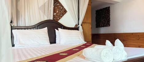 A bed with a canopy, a wooden headboard, and a red and gold bedspread.