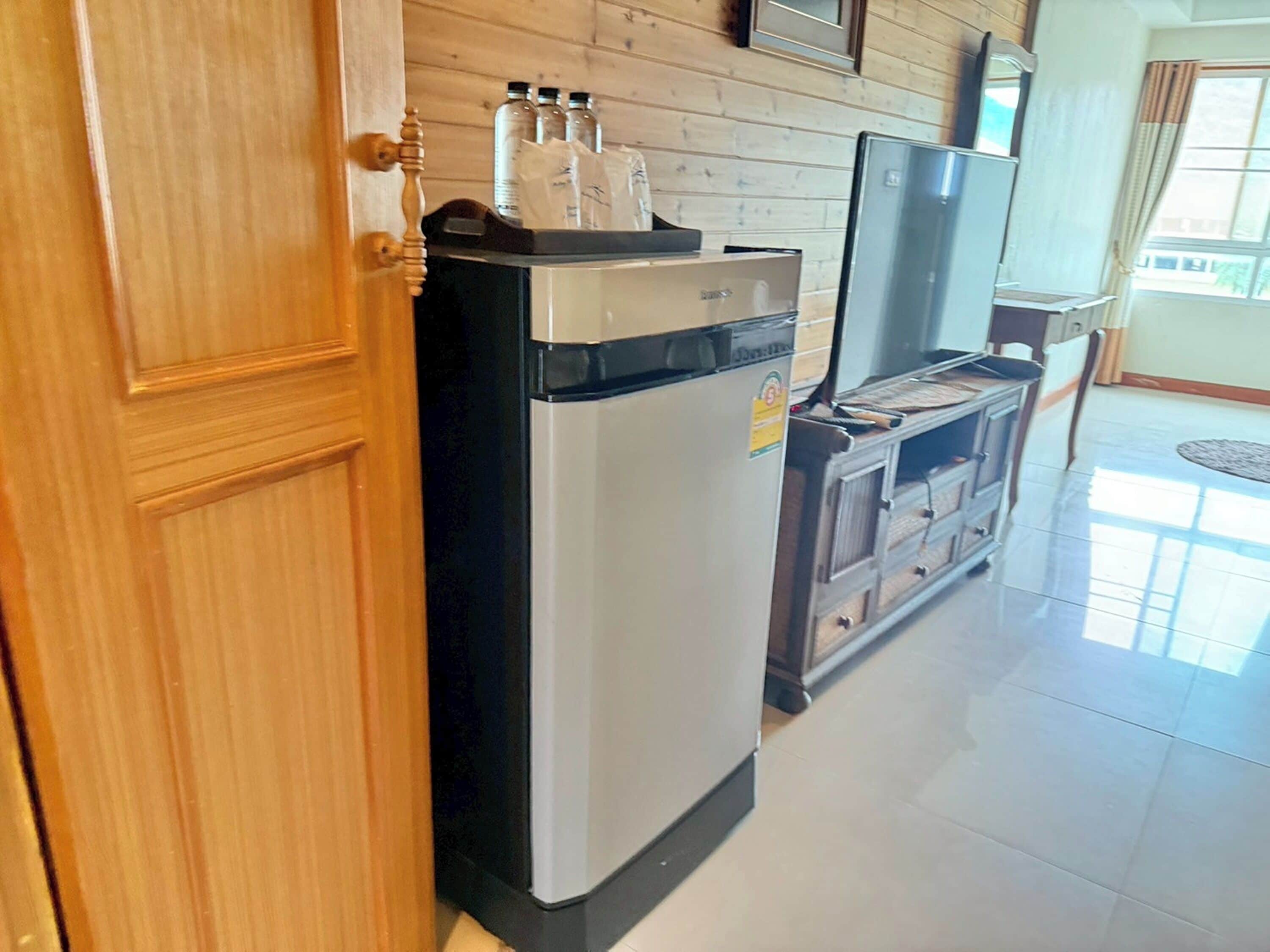 A kitchen with a refrigerator, a microwave, and a wooden cabinet.