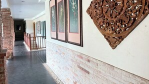 Un pasillo con obras de arte enmarcadas en la pared, pared de ladrillo y un adorno de madera.