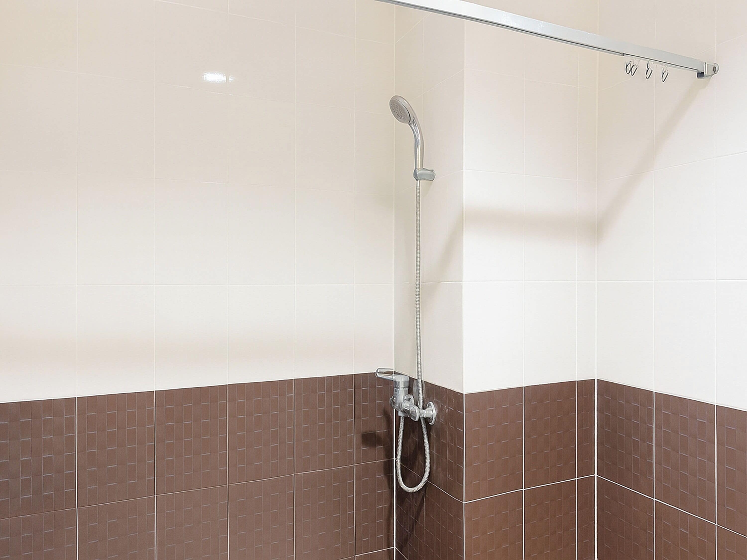 A shower area with a glass partition, a showerhead, and a towel rack.