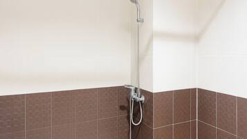 A shower area with a glass partition, a showerhead, and a towel rack.