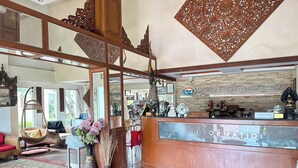 Un área de recepción con un mostrador de madera, un letrero que dice 'Recepción' y un letrero que dice 'Maekhong Delta Travel Agency Co. Ltd.'.