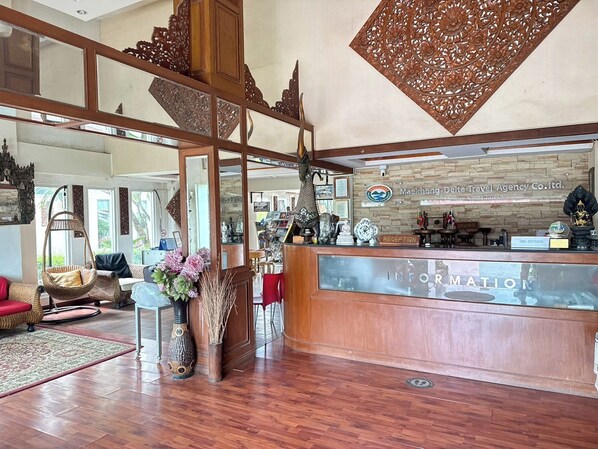 Uma área de recepção com balcão de madeira, placa indicativa e diversos objetos decorativos.