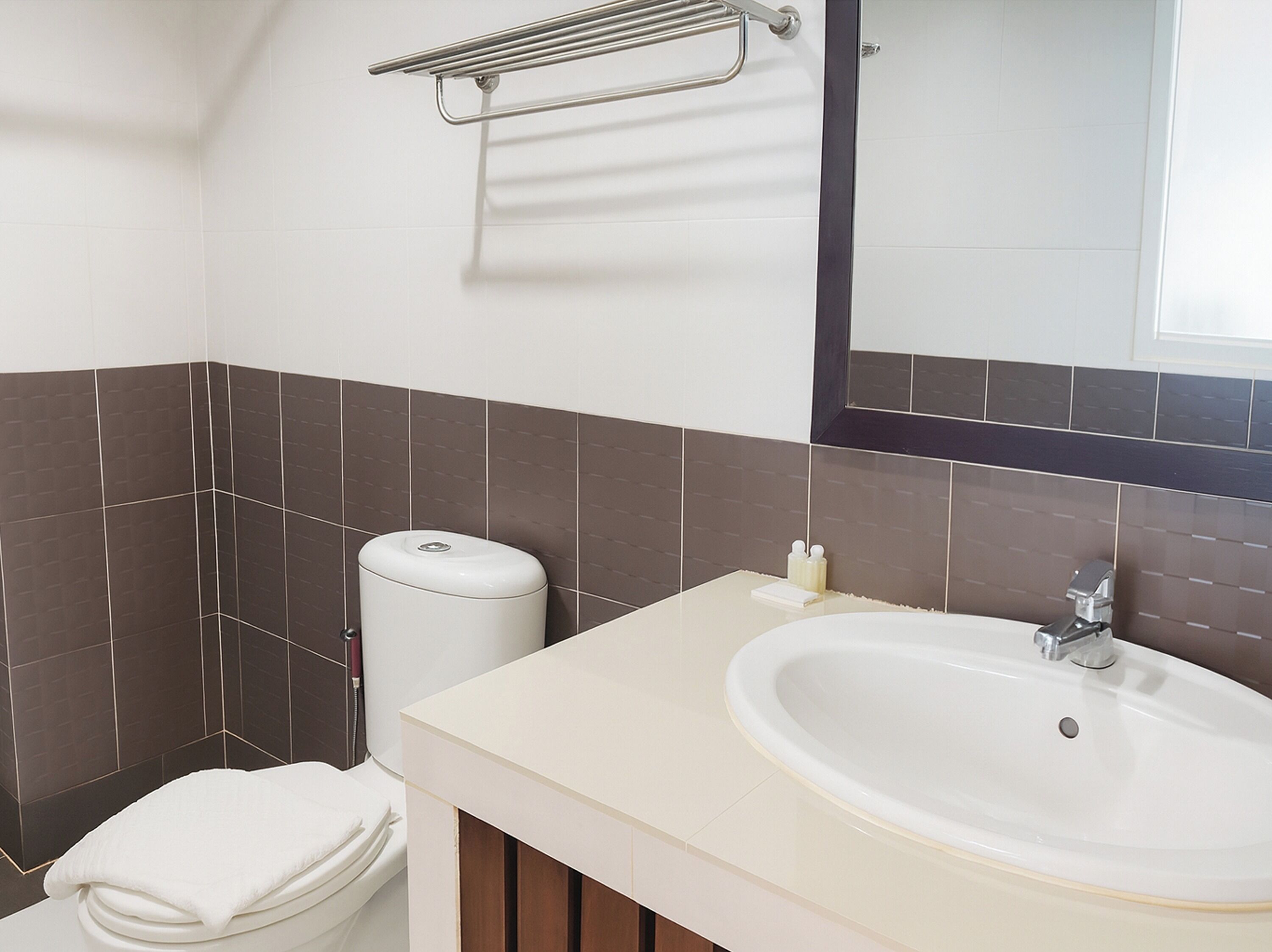A bathroom with a toilet, sink, and mirror.