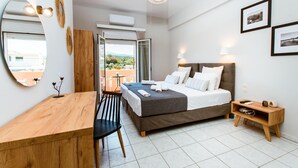 A modern hotel room with a bed, bedside table, and a desk with a chair. - Koulouris Apartments (Apokoronas)