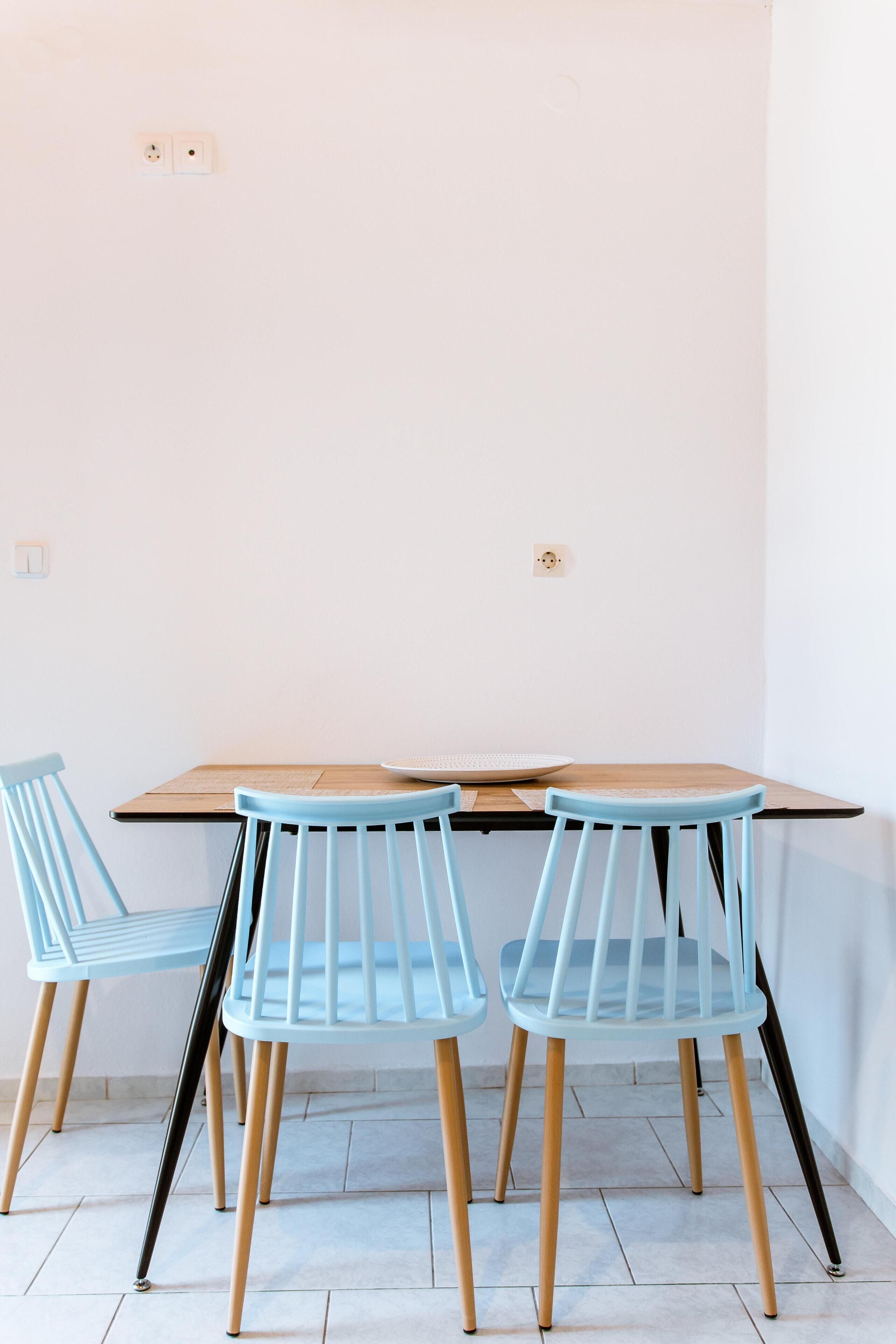 A dining area with a wooden table and two light blue chairs with wooden legs.
