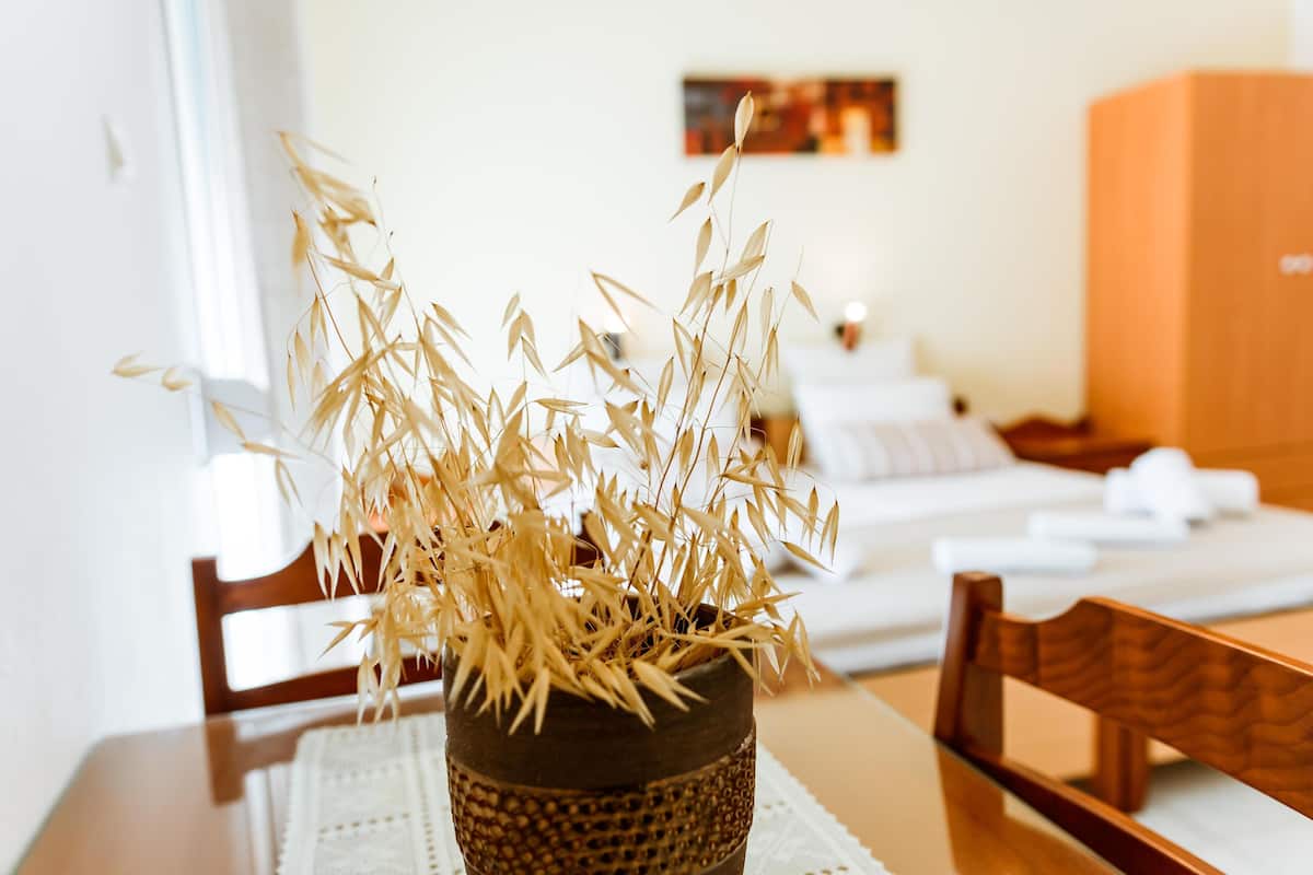 A dining table with a woven basket containing dried plants, a wooden chair, and a white table runner.