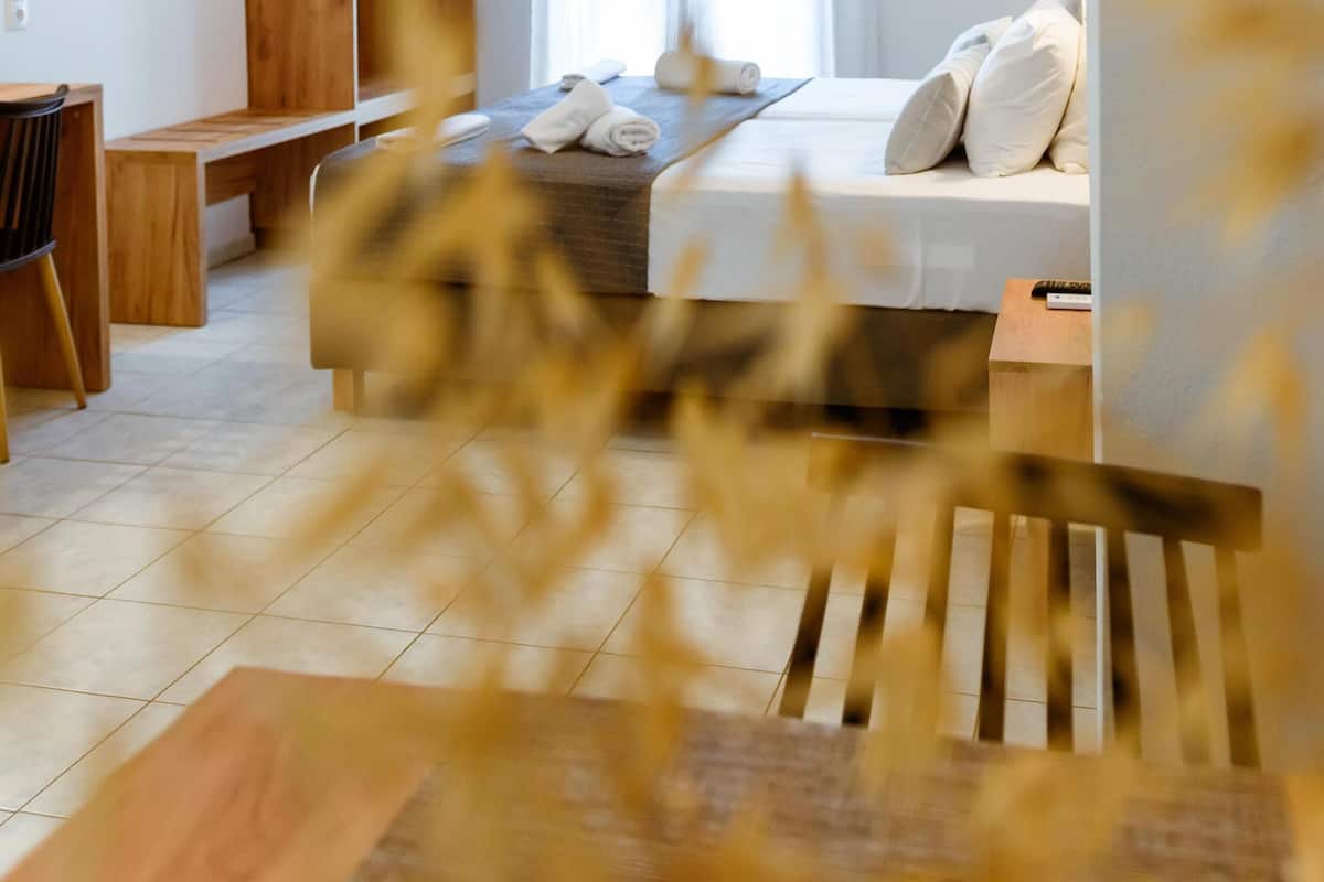 A modern hotel room with a bed, a desk, a wardrobe, and a hanging light fixture.
