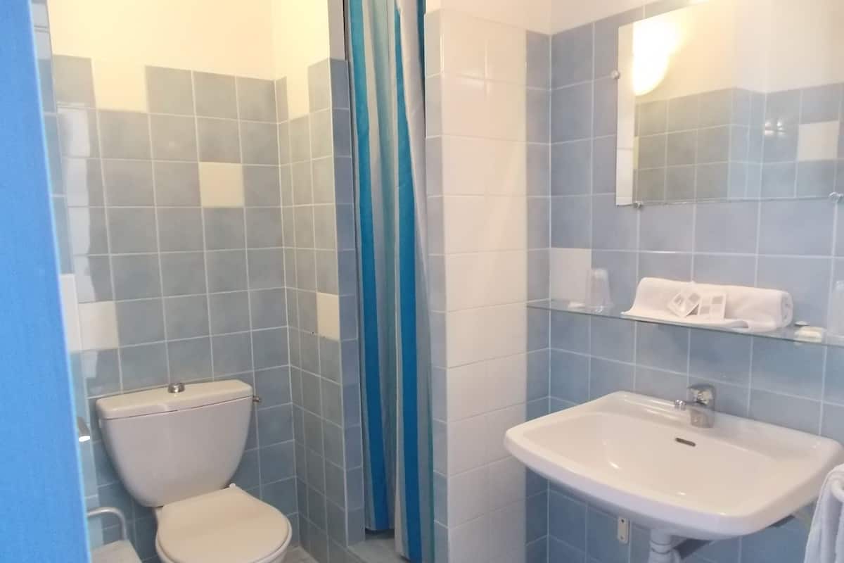 Un baño con inodoro, lavamanos y cortina de ducha.
