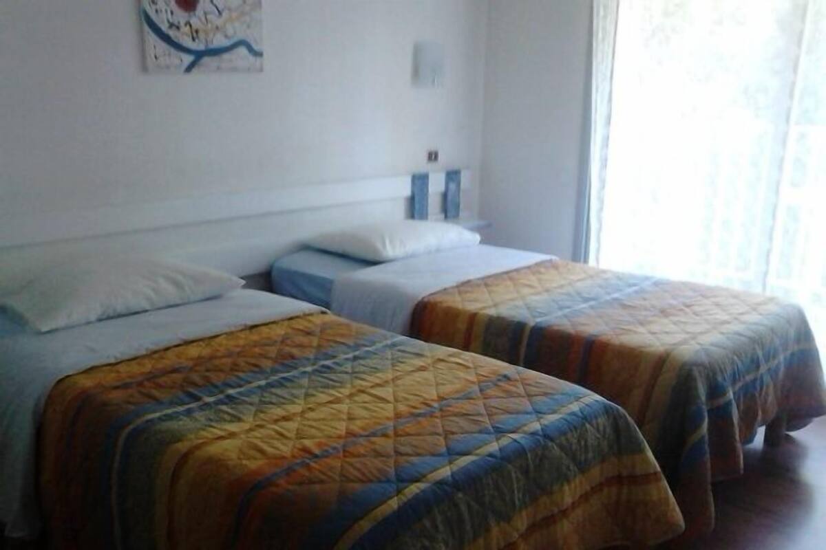Una habitación de hotel con dos camas individuales, un mapa en la pared y una ventana con cortinas.
