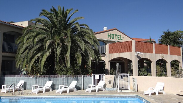 Um hotel com piscina, cadeiras de descanso brancas e uma palmeira.