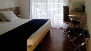 Quarto de hotel com cama, escrivaninha e cadeira.