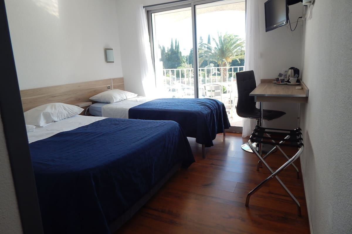 Habitación de hotel con dos camas, un escritorio, una silla y un televisor.