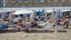 A beach with sun loungers and umbrellas, a building with balconies in the background, and a sign for Hotel Astor. - Hotel Marlisa Pier (Jesolo)