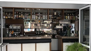 An outdoor bar area with a variety of liquor bottles, a coffee machine, and seating with chairs. - Hotel Marlisa Pier (Jesolo)