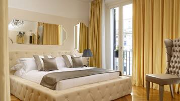 Un dormitorio amplio con una cama grande, una zona de estar y vistas a la ciudad desde la ventana.