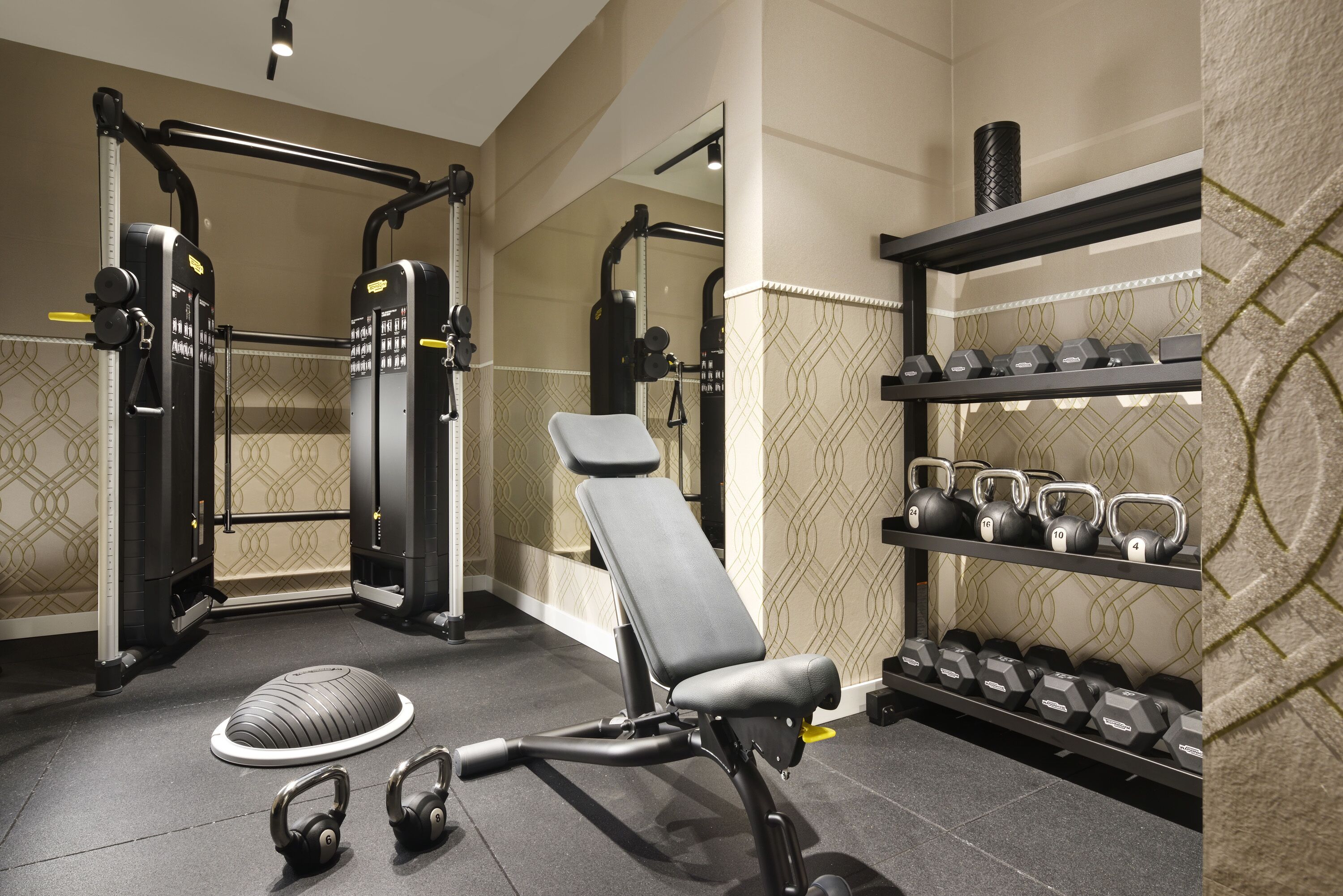 A gym with exercise equipment, a bench, and dumbbells.