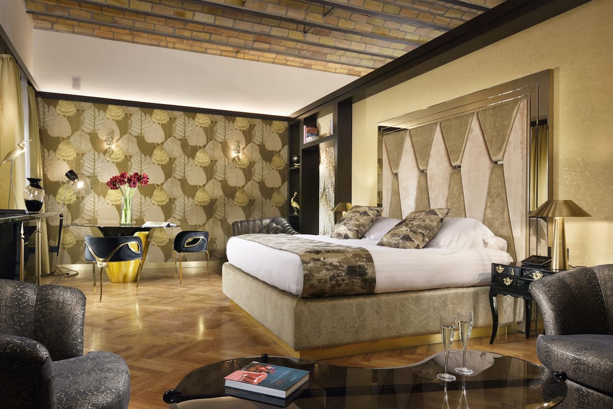 A well-appointed bedroom with a large bed, a glass coffee table, and a seating area with chairs.