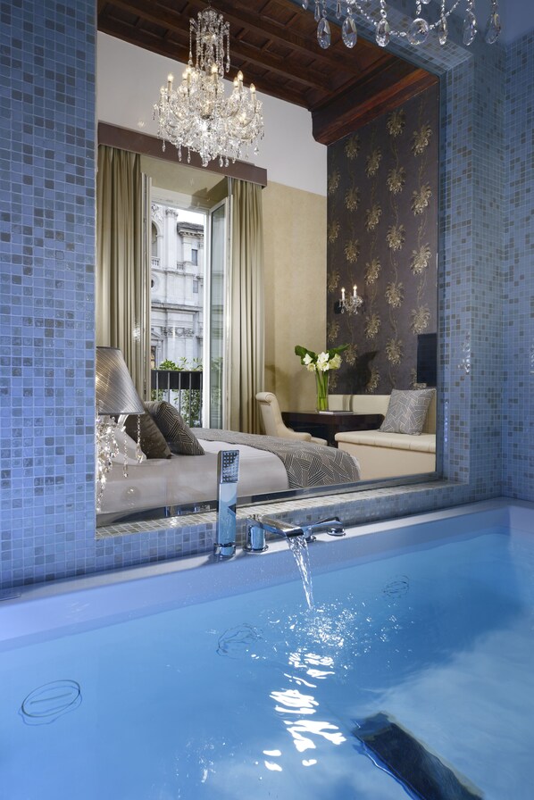 A modern bathroom with a large mirror, a bathtub, and a chandelier.