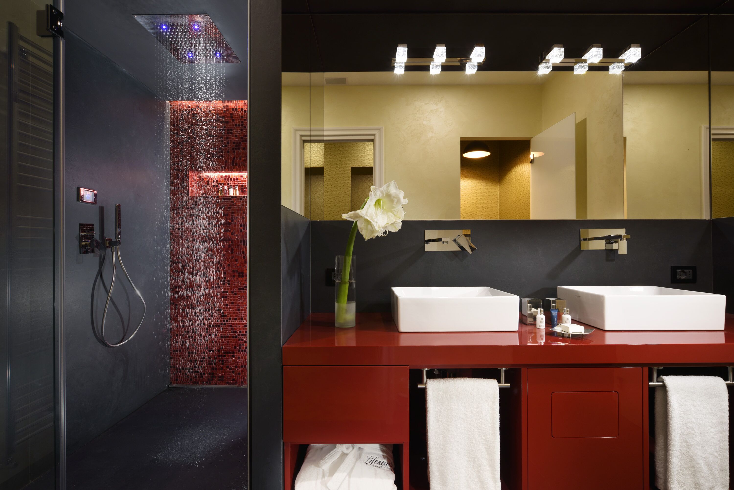 Un baño moderno con ducha, dos lavamanos y un espejo grande.