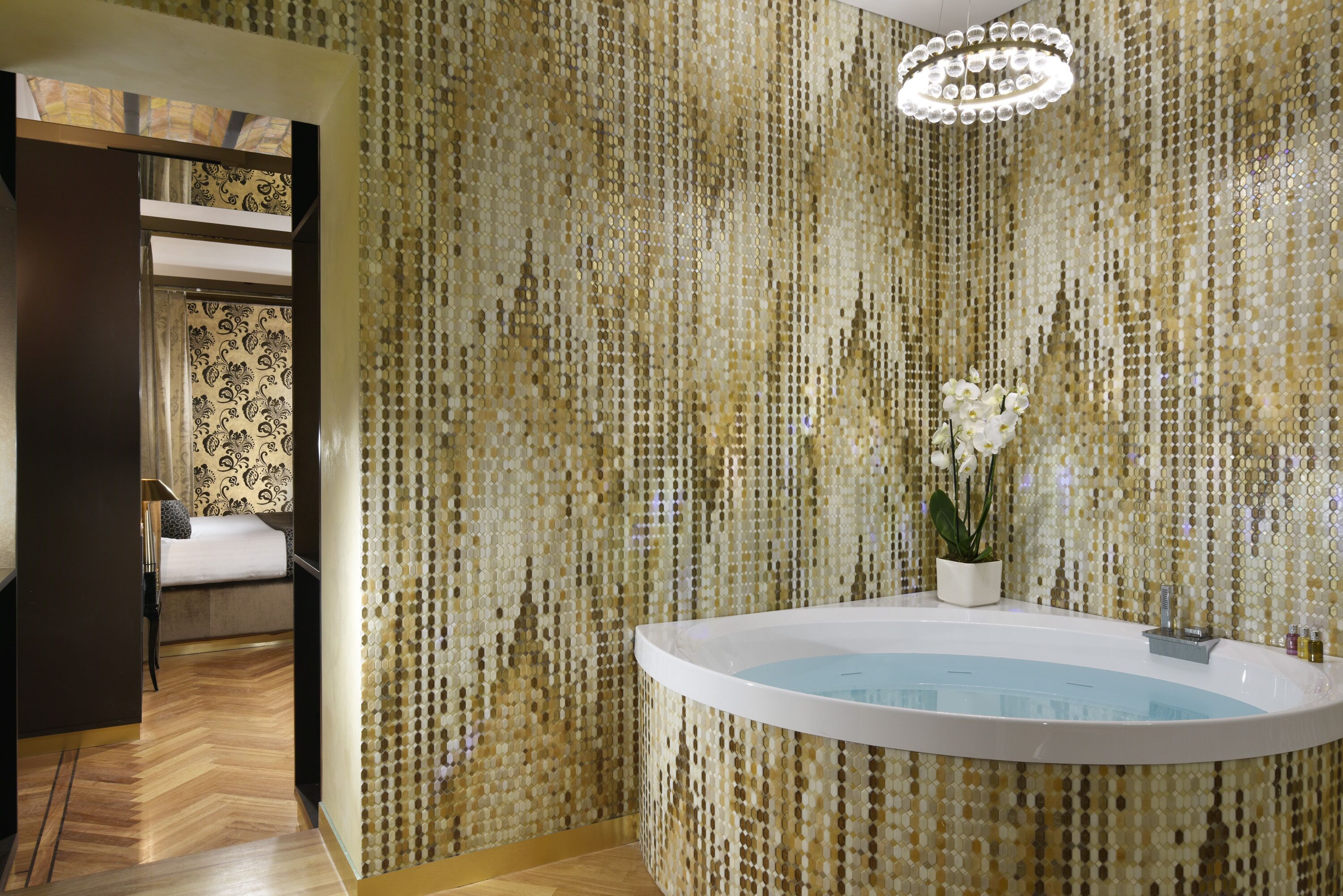 A bathroom with a freestanding bathtub, a potted plant, and a decorative mirror.