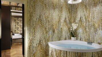 A bathroom with a freestanding bathtub, a potted plant, and a decorative mirror.