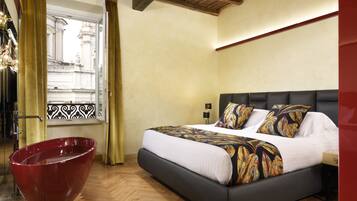 A bedroom with a large bed, a red bathtub, and a window with a view of a building.