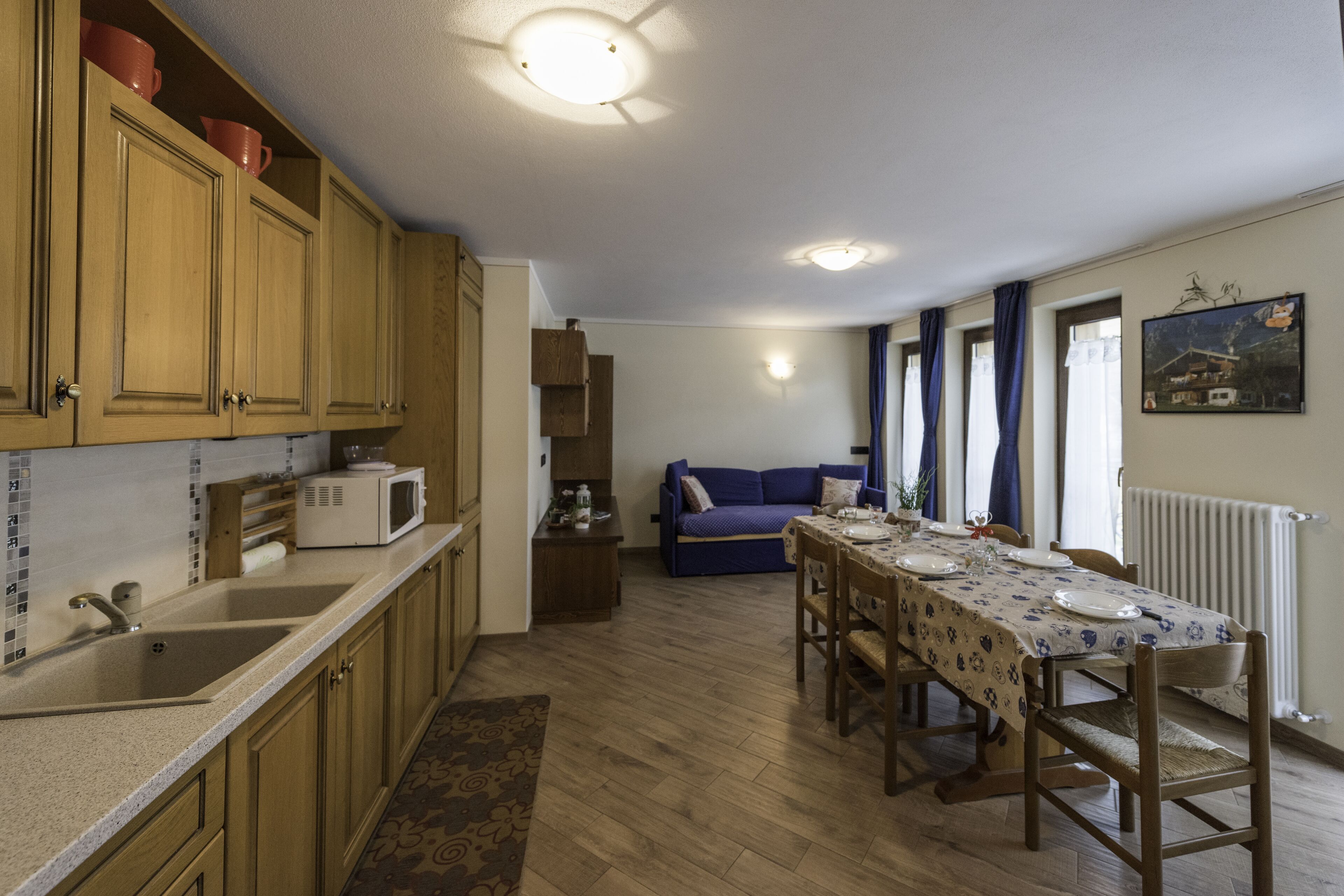 A kitchen with wooden cabinets, a microwave, and a dining area with a table set for two.