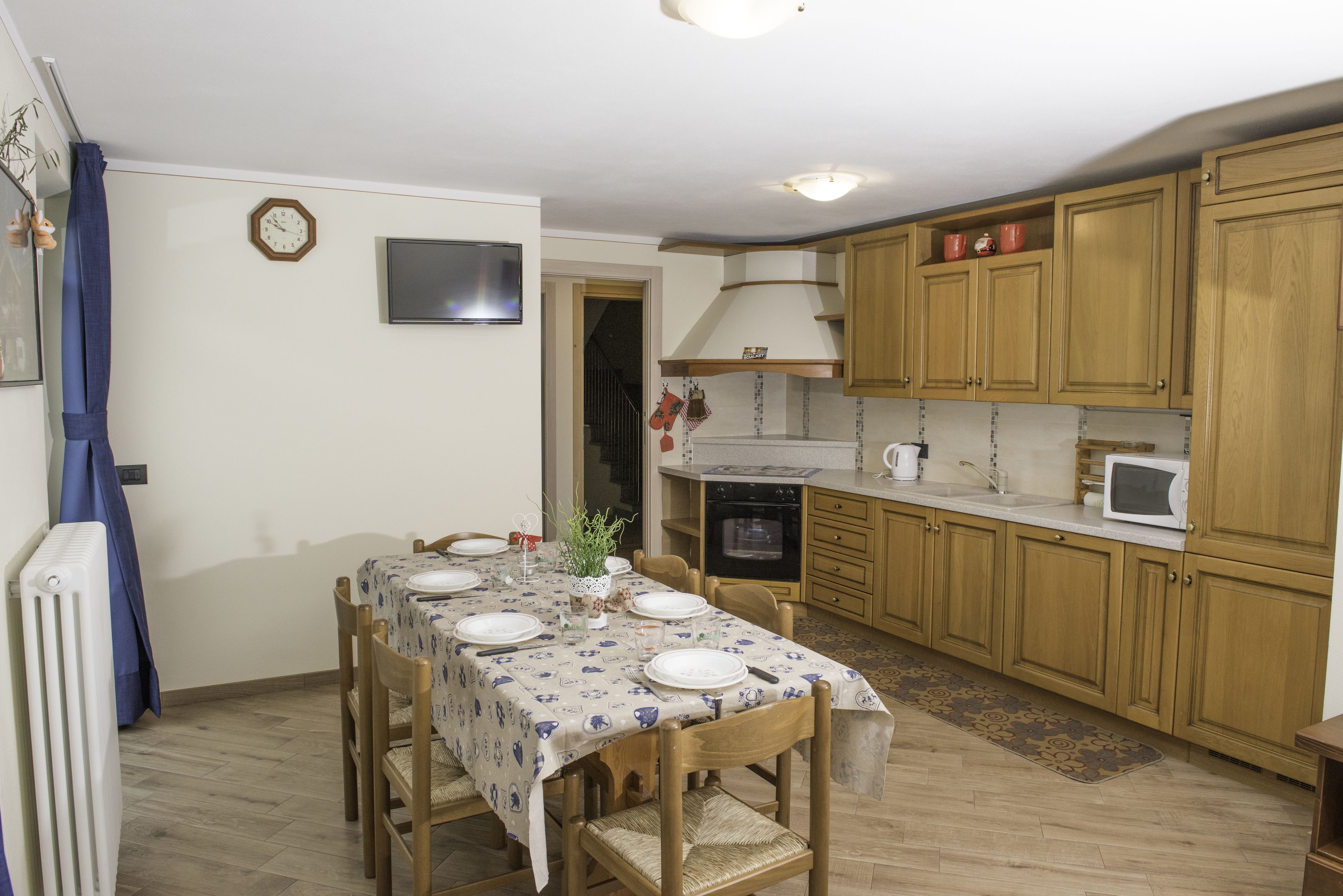 Una cucina con mobili in legno, un tavolo da pranzo per quattro persone e un forno integrato.