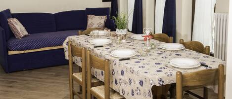 Uma área de jantar com uma mesa posta para quatro pessoas, rodeada por cadeiras de madeira.