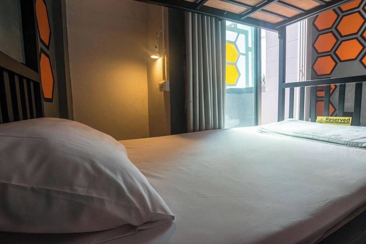 Una habitación de hotel con una cama, un ventanal con cortinas y un cartel que dice 'Reserved'.