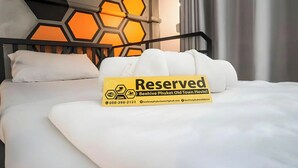 A bed with a 'Reserved' sign, a honeycomb-patterned headboard, and a white pillow.