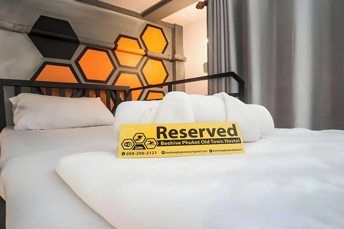 Una cama con un letrero que dice 'Reserved', un cabecero con diseño de panal y una almohada blanca.