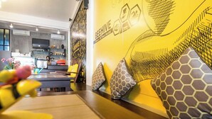 A modern hostel interior with a long communal table, patterned cushions, and a wall mural.